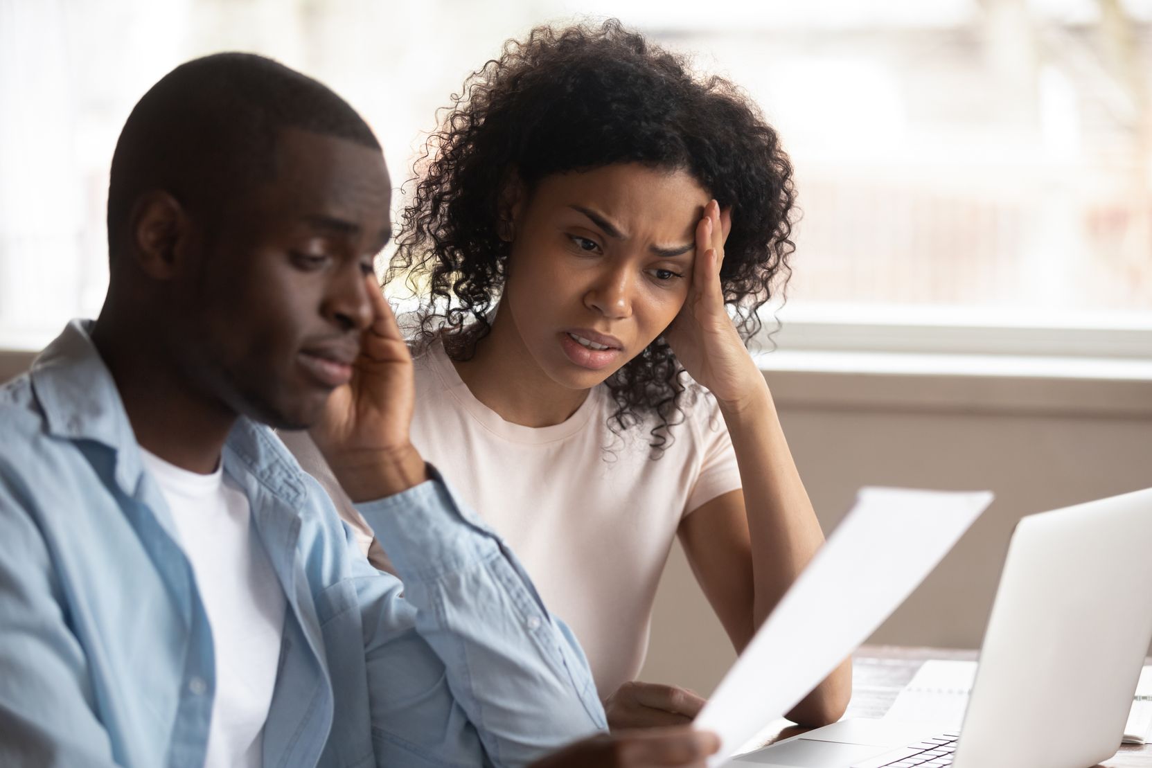 African American couple assessing their finances together with distressed faces.